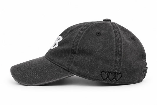 Washed black dad hat with three black signature hearts embroidered on the side