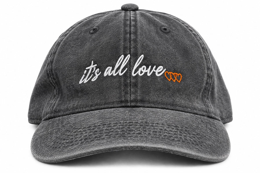Washed grey dad hat with white it’s all love script and three orange signature hearts embroidered on front